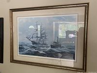 Full view of framed print showing large sailing ship and smaller steamboat navigating sea waves under cloudy sky.