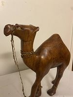 Front view of wooden camel carving showing head with braided rope harness and eye details.