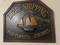 Front view of the wooden wall plaque showing the raised 3D ship and detailed text in gold and beige lettering on black background.