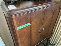 Front view of vintage wooden cabinet with decorative doors and measuring tape showing dimensions.