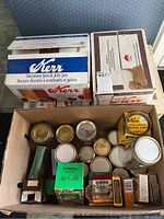 Photo showing boxes of Kerr canning jars, loose jars, and several boxes of lids and caps including Bernardin snap lids and Kerr wide mouth caps.