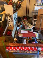 Overview of Christmas supplies showing multiple rolls of wrapping paper, ribbons, artificial flowers, and wreaths in boxes and cart