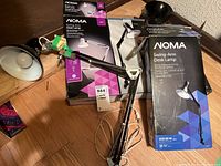 Photo of five clamp-on desk lamps including multiple boxed and unboxed NOMA Swing-Arm Desk Lamps with adjustable clamp bases.