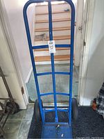 Full view of the blue metal hand cart showing its tall frame and loading platform.