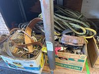 Boxed assortment of leather belts and coils of rope