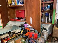 Wooden cabinet shelf containing ear protection headphones, soldering supplies, small tools and boxes