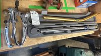 Full lot view showing the torque wrench in its case, the gear puller, and the metal rod tool on a wooden surface.