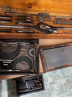 Overview of wooden case with taps, dies, wrench, gauges, and micrometers visible.