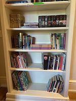 White shelving unit with books arranged on four visible shelves