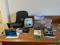 Lot laid out on table with all cameras, accessories, camera cases, and film displayed