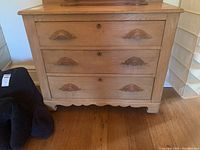 Front view of antique pine dresser showing three drawers with moustache-shaped wooden drawer pulls.