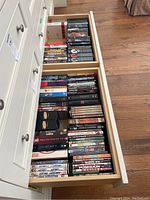Two bottom drawers filled with DVDs showing a variety of movies and TV series stacked in organized rows.