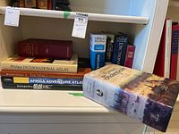 Shelf view showing atlases and dictionaries including Philip's International Atlas, Africa Adventure Atlas, The New York Times Atlas of the World, Concise Oxford English Dictionary, Le Robert & Collins Dictionnaire Anglais