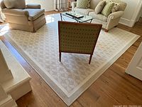 Overall view of square area rug laid in living room under furniture