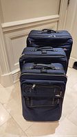 Three Samsonite suitcases stacked viewed front and side, showing sizes and general condition.