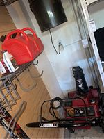 Snowblower at floor level with two gas cans on shelf above
