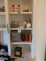 Full view of shelf including piggy banks, toy safe, leather figurines, and photo box