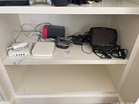 Shelf with Apple TV boxes, Crestron remote, Wi-Fi touch panel and Android TV box visible with cables