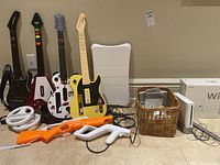 Four guitar controllers, two white steering wheels, four Zapper shells, sensor bar and console box