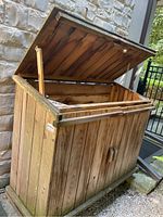Open wooden storage cabinet showing sloped hinged lid and interior