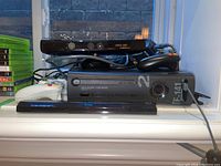 Xbox 360 console with Task Force 141 edition label, two controllers stacked on top, Kinect sensor, and cables.