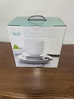 Box photo showing the 12 piece porcelain dinnerware set with bowls and plates stacked and a pear as decoration on the box artwork.