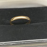 Front profile view of plain gold band in display case