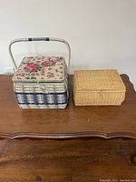 Two closed sewing boxes, a square floral basket with handle and a smaller rectangular wicker basket