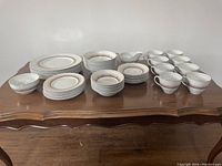 Entire set arranged on wooden table showing all plates, bowls, cups, and serving pieces