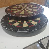 Two dart boards stacked on top of each other showing edge and surface wear.