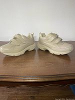 Side view of the beige orthopedic shoes showing the leather upper and Velcro straps.