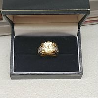Front view of the yellow cubic zirconia ring set in a gold-tone band inside a black jewelry box with a white interior.