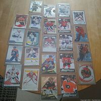 Top-down image of 23 Upper Deck hockey cards spread out in a grid on a wooden table. Includes cards with full player images, autograph inserts, and special edition designs mostly from the 2015/2016 season.