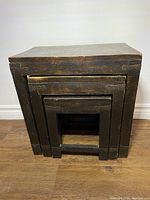 Photo showing three wood nesting tables stacked one inside another, displaying different sizes.