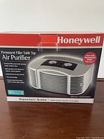 Box showing Honeywell Signature Series Permanent Filter Table Top Air Purifier, highlighting permanent filter feature and compact design.