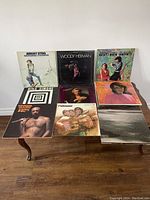 Top view of 9 assorted vinyl records laid out on table showing album cover art and artists names such as Nina Simone and Woody Herman