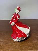 Front view of the Royal Doulton figurine showing the lady in red dress with detailed folds and white accents