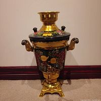 Front view of the samovar showing the painted floral decoration, handles, spigot, and ornate base.