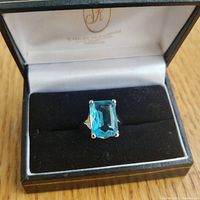 Top view of the ring showing the large rectangular blue stone set in the band inside a jewelry box.