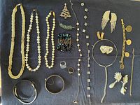 All 18 assorted vintage jewelry items displayed on surface, including necklaces, earrings, bracelets, rings, and pins.
