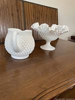 Side view of vintage Fenton Hobnail milk glass pitcher and fluted bowl on wooden table, showing details of hobnail pattern and shapes