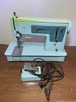 Front and side view of light blue vintage Singer sewing machine with foot pedal and attached power cord.