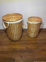 Two sized wicker laundry baskets side by side with lids on, showing overall appearance and size difference.