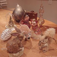 Lot of winter animal and glass blown Christmas tree ornaments arranged on wooden surface. Includes rabbit, squirrel, fox, pinecone, and glass dome decorations.