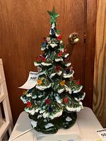 Front view of the green ceramic Christmas tree with colorful light bulbs and green star topper.