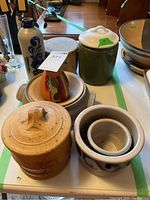 Top view of the lot showing various stoneware ceramics including bottle, signed dish, bowls, and canister.