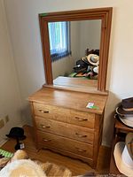 Front view of the wood dresser with mirror showing three drawers and metal pulls.