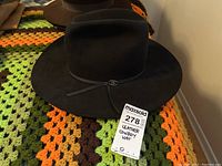Top down photo of black leather cowboy hat with wide brim and grosgrain ribbon band.