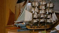 Photo showing three model ships on a wooden shelf including a large Cutty Sark model with detailed rigging and sails.