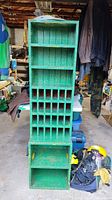 Front view of green painted solid wood shelving unit showing two top shelves, grid of cubby holes and bottom shelf